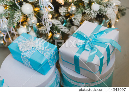 Christmas gift boxes with blue bow and bokeh lights on wooden surface Christmas gift boxes with blue bow and bokeh lights on wooden surface 44545097