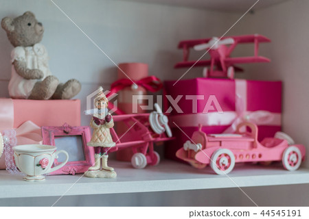 Christmas gifts in box on a shelf, pink car, airplane, wooden horse and gingle bell. Christmas gifts in box on a shelf, pink car, airplane, wooden horse and gingle bell. 44545191