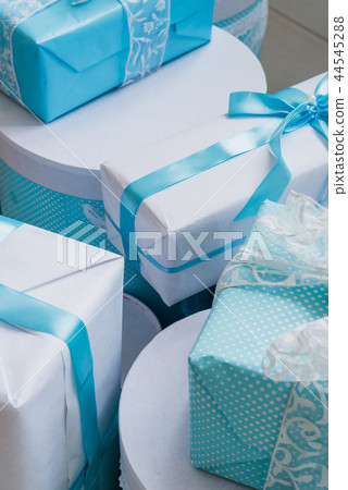 Christmas gift boxes with blue bow and bokeh lights on wooden surface Christmas gift boxes with blue bow and bokeh lights on wooden surface 44545288
