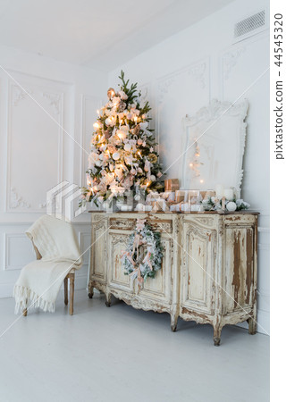 Christmas tree on wooden chest of drawers commode bureau in white interior, decorated with Christmas tree on wooden chest of drawers commode bureau in white interior, decorated with 44545320