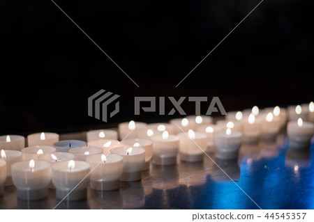 Close-up detail of multiple short candles lighting up a church. Travel and religion concept. Close-up detail of multiple short candles lighting up a church. Travel and religion concept. 44545357