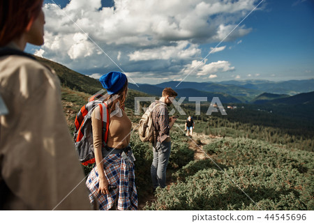 Four young hikers are travelling in mountains Four young hikers are travelling in mountains 44545696