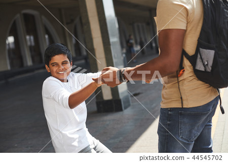 Smiling hindu boy holding his fathers hands 44545702