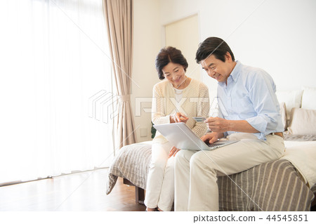Senior couple personal computer bedroom lifestyle image 44545851