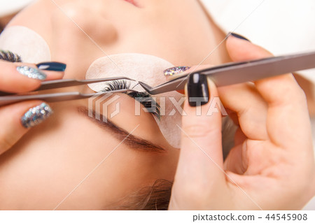 Eyelash Extension Procedure. Woman Eye with Long Eyelashes. Close up, selective focus. Eyelash Extension Procedure. Woman Eye with Long Eyelashes. Close up, selective focus. 44545908