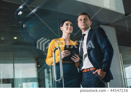 Confident smiling co-workers standing behind transparent wall 44547238