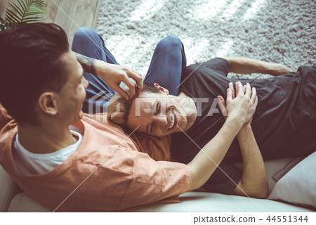 Happy gay couple resting on couch at home Happy gay couple resting on couch at home 44551344