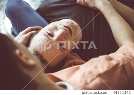 Loving gay couple relaxing together on couch at home Loving gay couple relaxing together on couch at home 44551345