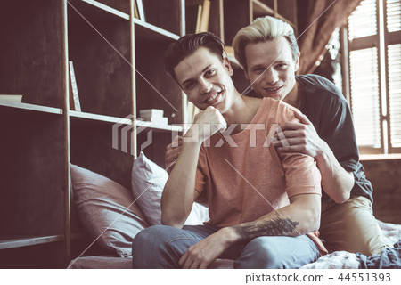Young gay couple sitting on bed and smiling 44551393