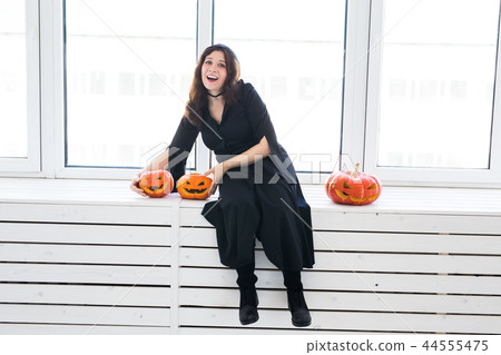 Halloween and holidays concept - Witch woman with Jack O'Lantern pumpkin 44555475