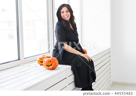 Halloween concept - Happy witch with pumpkin Jack-o'-lantern on light background Halloween concept - Happy witch with pumpkin Jack-o'-lantern on light background 44555483