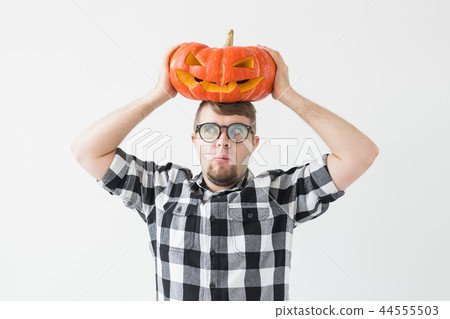 Funny handsome bearded man with carved halloween pumpkin over light background Funny handsome bearded man with carved halloween pumpkin over light background 44555503