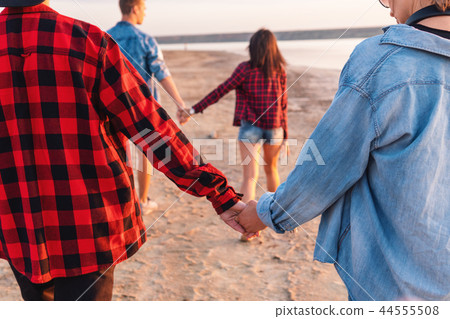 friends on beach together walking during sunset friends on beach together walking during sunset 44555508