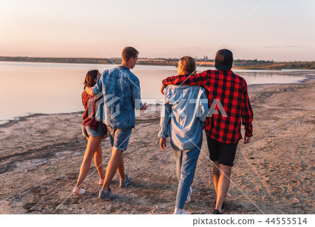 friends on beach together walking during sunset friends on beach together walking during sunset 44555514