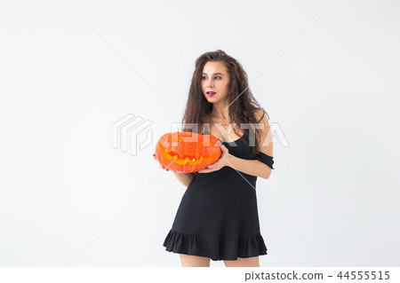 Halloween concept - Happy witch with pumpkin Jack-o'-lantern on light background with copy space 44555515