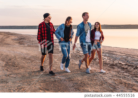 friends on beach together walking during sunset friends on beach together walking during sunset 44555516