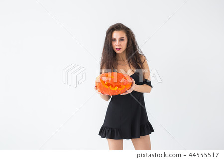 Happy gothic young woman in witch halloween costume smiling over white room background with copy Happy gothic young woman in witch halloween costume smiling over white room background with copy 44555517