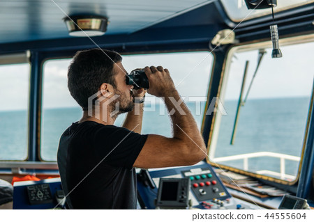 Navigational officer lookout on navigation watch looking through binoculars 44555604