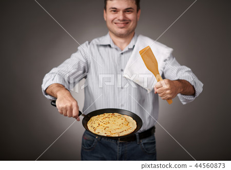 man posing with a pancake in a pan, white shirt 44560873