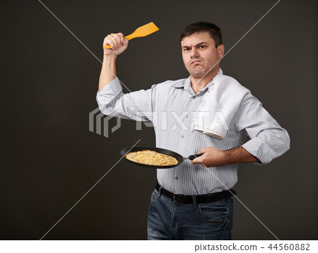 man posing with a pancake in a pan, white shirt 44560882