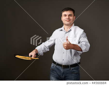 man posing with a pancake in a pan, white shirt 44560884
