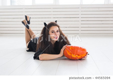 Portrait of a stylish brunette woman with halloween pumpkin Portrait of a stylish brunette woman with halloween pumpkin 44565094