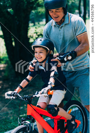 Grandfather and grandson biking in the park Grandfather and grandson biking in the park 44566796