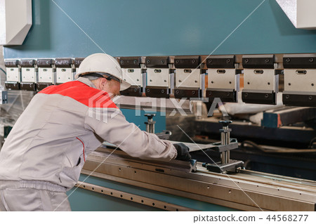 Tool and bending equipment for sheet metal. manufacture workshop. Workers adjusts the machine in the Tool and bending equipment for sheet metal. manufacture workshop. Workers adjusts the machine in the 44568277