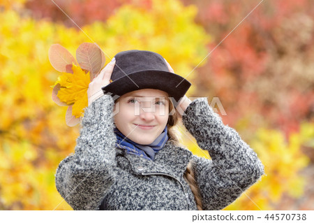 Smiling girl in hat in autumn park. Bright foliage 44570738