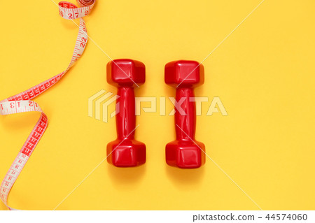 Two red dumbbells and tape measure. Fitness concept 44574060