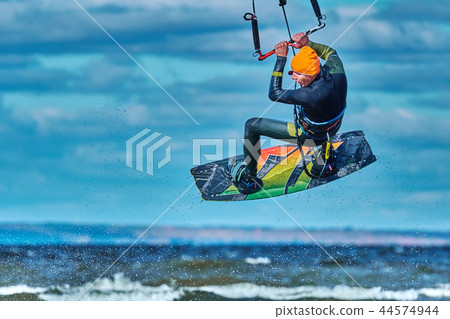 A male kiter jumps over a large lake. Close-up. A male kiter jumps over a large lake. Close-up. 44574944