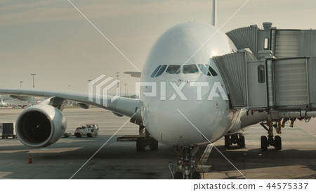 Passengers board a huge airliner at the hub. Visible silhouettes of people entering the plane 44575337