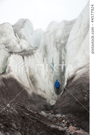 A free climber with an ice ax in his hand stands at the foot of the Great Glacier next to an epic 44577924