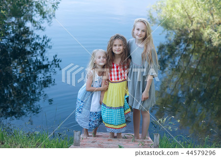 children on the riverbank / summer vacation merry girlfriends on vacation, sisters together on the river, friendship happiness family children on the riverbank / summer vacation merry girlfriends on vacation, sisters together on the river, friendship happiness family 44579296