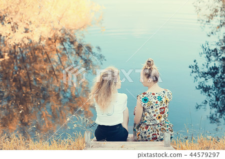 children on the riverbank / summer vacation merry girlfriends on vacation, sisters together on the river, friendship happiness family 44579297