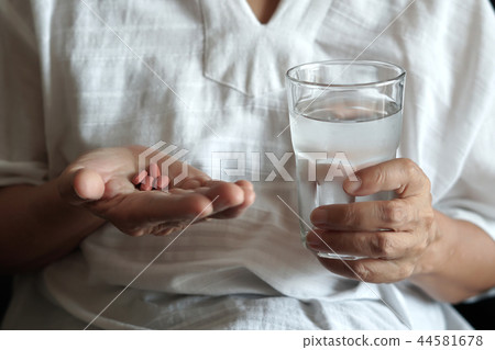 elderly woman are  eating medicine and with pills 44581678