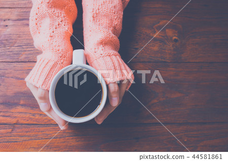 Woman hand in warm sweater holding a cup of coffee Woman hand in warm sweater holding a cup of coffee 44581861