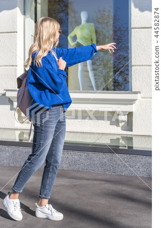 Woman points finger at shop window Woman points finger at shop window 44582874