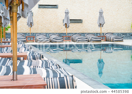 umbrella and chair around outdoor swimming pool 44585398