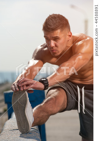 Close-up shirtless young male jogger warmimg up 44588891