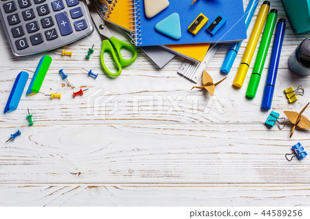 On a white table in a chaotic order lie: calculator, elastic, paper clips. Back to school background 44589256