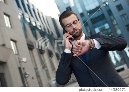 A young businessman in glasses and with a beard arranges a meeting 44589671
