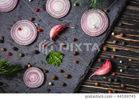 Pepper peas scattered randomly, onion, garlic and dill on a dark background Pepper peas scattered randomly, onion, garlic and dill on a dark background 44589745