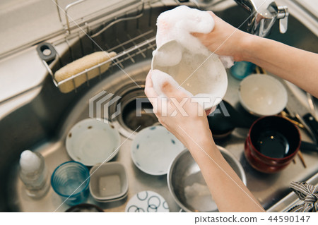 Young housewife washing utensils in kitchen 44590147