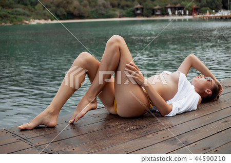 Sensual female lying on pier 44590210