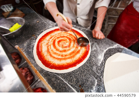 Cooking pizza. Imposition of tomato paste on the dough 44590579