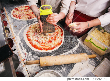 Adding cheese to pizza. Stages of cooking pizza. 44592150