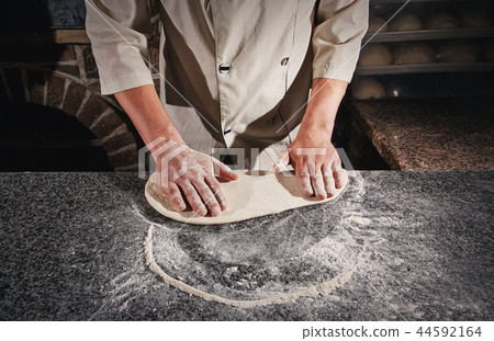 A dough for a pizza in the hands of the chef. 44592164