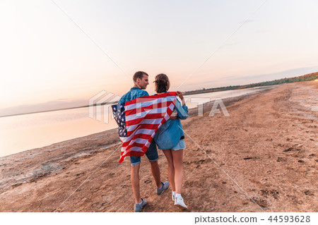 american couple covered in american flag walking on beach american couple covered in american flag walking on beach 44593628