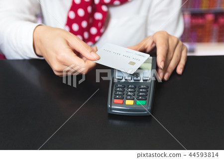 Hands of a female shop assistant holding a credit card and makin 44593814